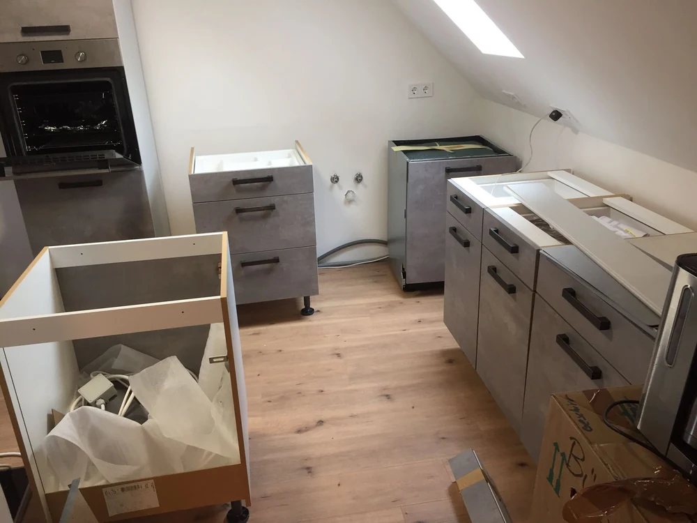 Graue Küchenunterschränke während der Montage unter einer Dachschräge