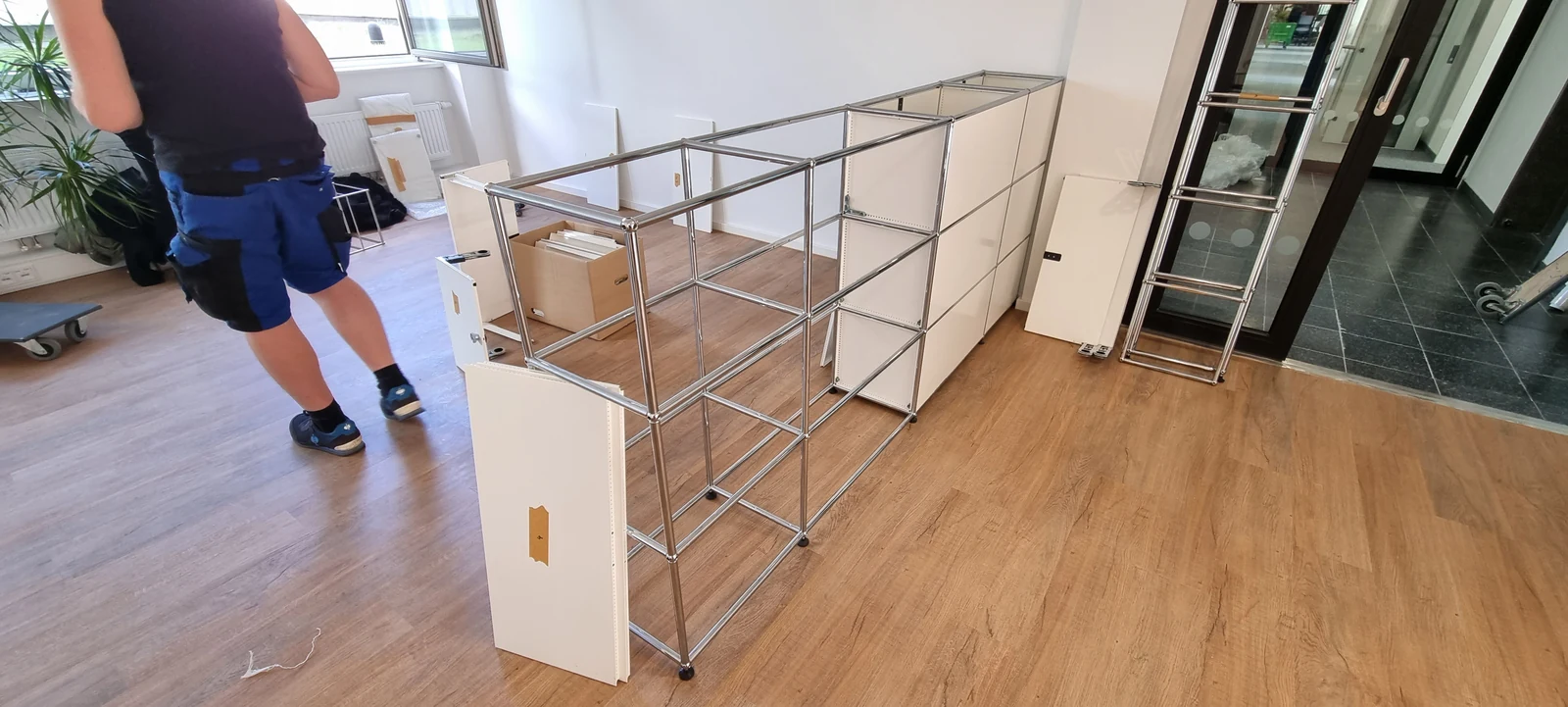 Freigelegter Chromrahmen einer USM-Haller-Schrankkombination während der Montage